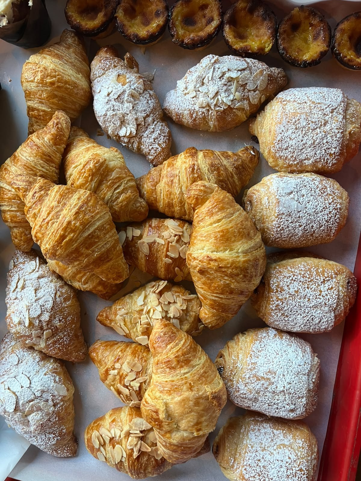Golden plain and almond croissants alongside pastries