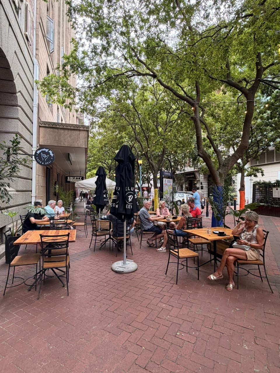 Guests enjoying coffee at the leafy outdoor café tables